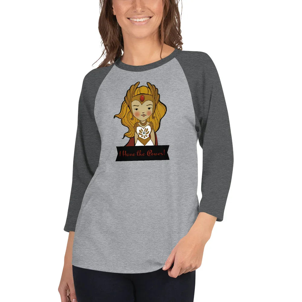 Woman wearing gray raglan tee with whimsical She-Ra illustration and 'I Have the Power!' text